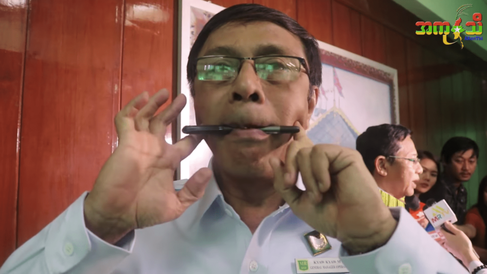 Myanmar Railways General Manager U Kyaw Kyaw Moe demonstrating how to smile with a pen – screengrab via Akonthi video