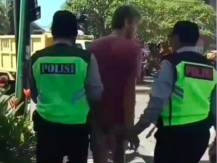 The Ubud shoplifter being escorted by police. Photo: Still from a video posted on Facebook by @ORTI Badung