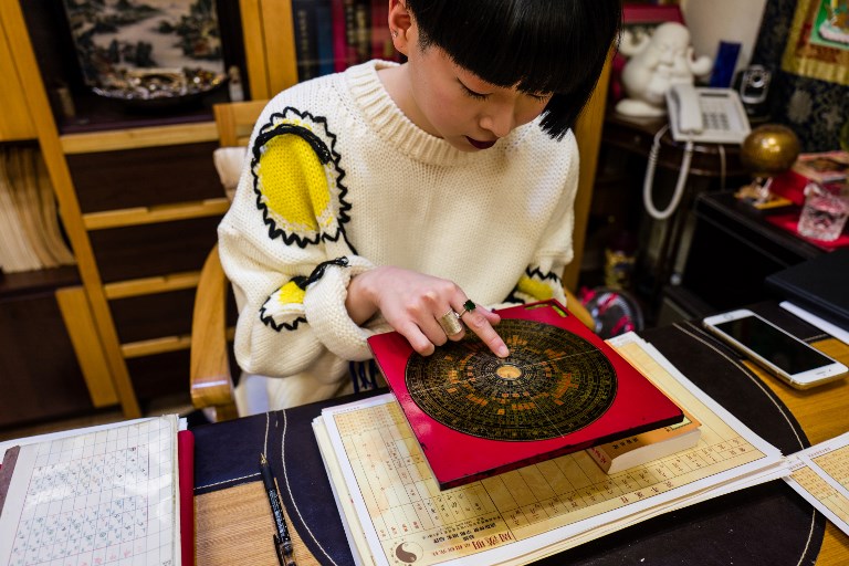 Feng shui master Thierry Chow consults a luopan, or Chinese compass, at her office in Hong Kong ahead of the Lunar New Year. Photo via AFP.