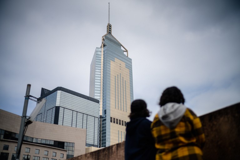 Saudi sisters Rawan (in yellow) and Reem stand in front of a view of the building which houses the Saudi consulate in Hong Kong. Photo via AFP.