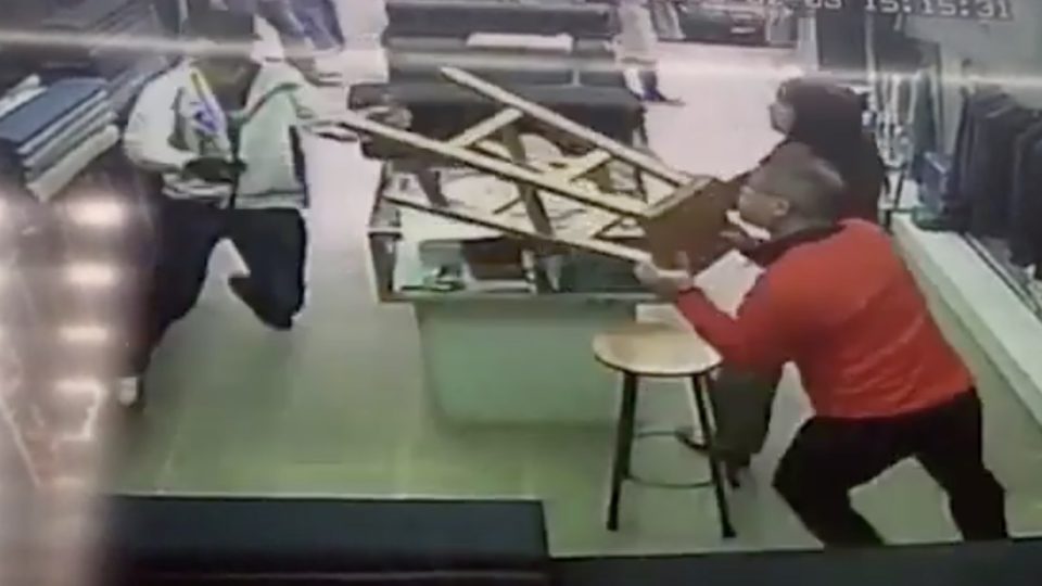 CCTV footage captures the moment a masked men runs into a tailor store tries to attack the owner with a 20-inch knife. The store’s owner tries to defend himself with a stool. Screengrab via Apple Daily video.