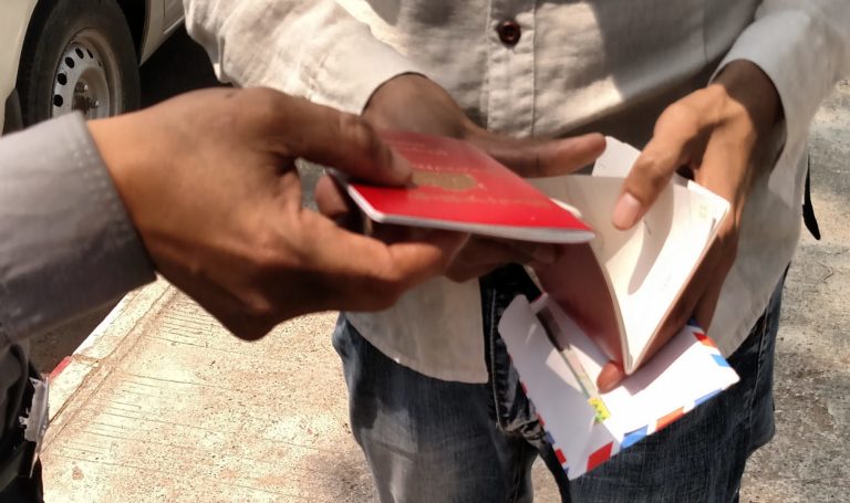 A passport applicant hands a bribe to a police officer named Pite Htwe on March 15, 2018 – Jacob Goldberg