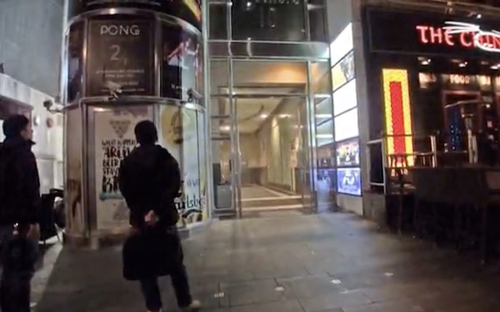 Police officers wait outside the entrance of Knutsford 10. Screengrab via Apple Daily video.