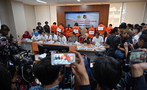 Suspects face the wall during a press conference by Indonesian officials in Jakarta, on April 9, 2019, about trafficking-related offences. – Indonesian police said they had arrested seven people linked to human trafficking cases involving more than 1,000 victims smuggled to the Middle East and North Africa. (Photo by BAY ISMOYO / AFP)
