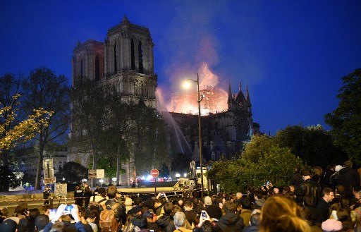 Crowds look on as flames and smoke billow from the roof at Notre-Dame Cathedral in Paris on April 15, 2019. (Photo: Eric Feferber/AFP)