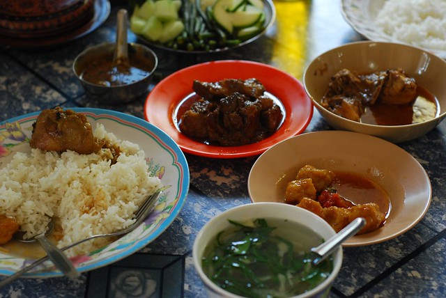 Traditional curry set with soup, rice, vegetables, fish sauce (condiments) and the curries – via Flickr by Vera & Jean-Christophe. 