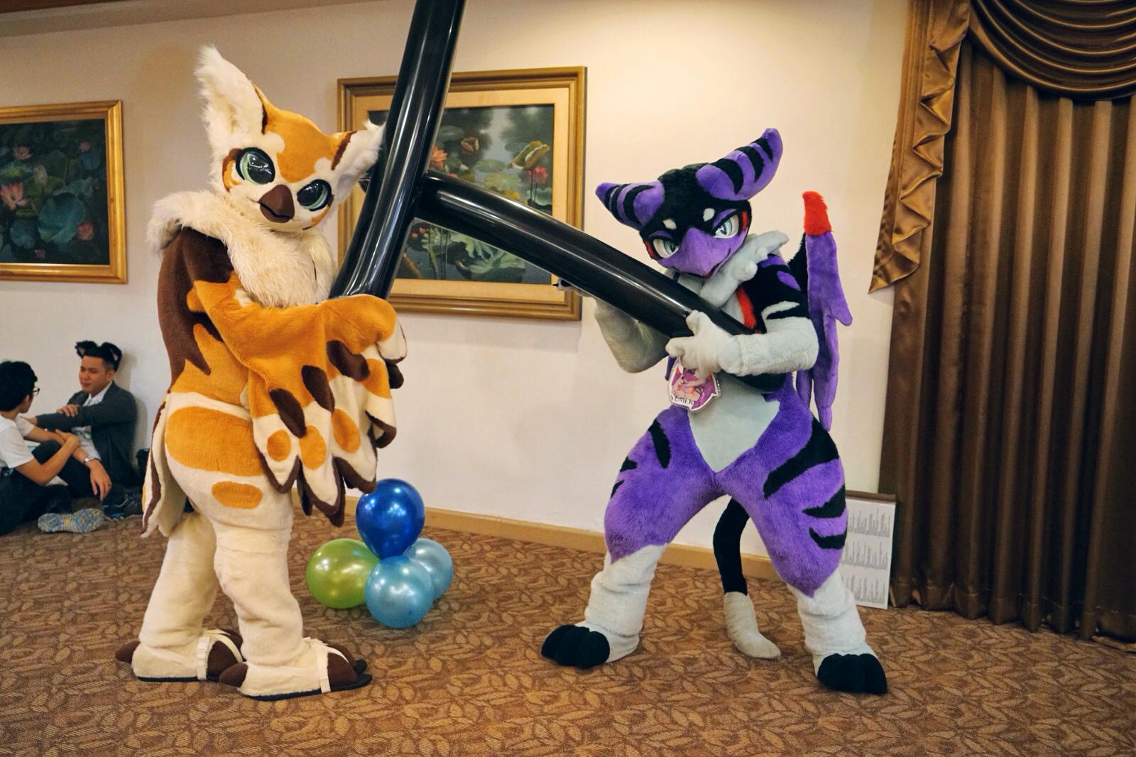 Two furries “sword fighting” with oversized long, black balloons