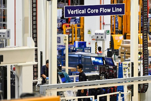 This photograph taken on March 18, 2019 shows technicians working at Rolls-Royce engine rotor assembly facility in Singapore. – Singapore has attracted high-tech manufacturers with incentives and a well-educated workforce but growing demands for highly skilled labour and government moves to curb numbers of foreign workers may mean a tougher path ahead. (Photo by Roslan RAHMAN / AFP) / TO GO WITH STORY Singapore-manufacturing-economy