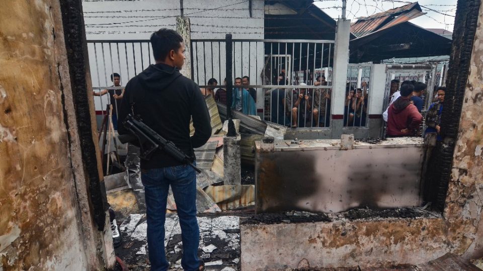 An armed plainclothes policeman (L) secures the around around Siak prison in Siak Sri Indrapura in Riau province on May 11, 2019 after rioting and a fire broke out at the detention centre leading to a prison break. – Hundreds of inmates on May 11 escaped from the Indonesian jail on Sumatra island, police said, the latest breakout to hit the countrys creaking prison system. (Photo by WAHYUDI / AFP)