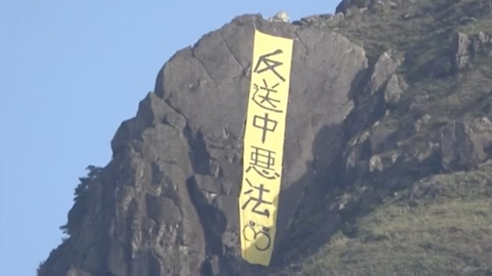 A yellow banner with the words “oppose the evil send-to-China law” was spotted hanging off the hillside of Kowloon Peak this morning. Screengrab via Apple Daily video.