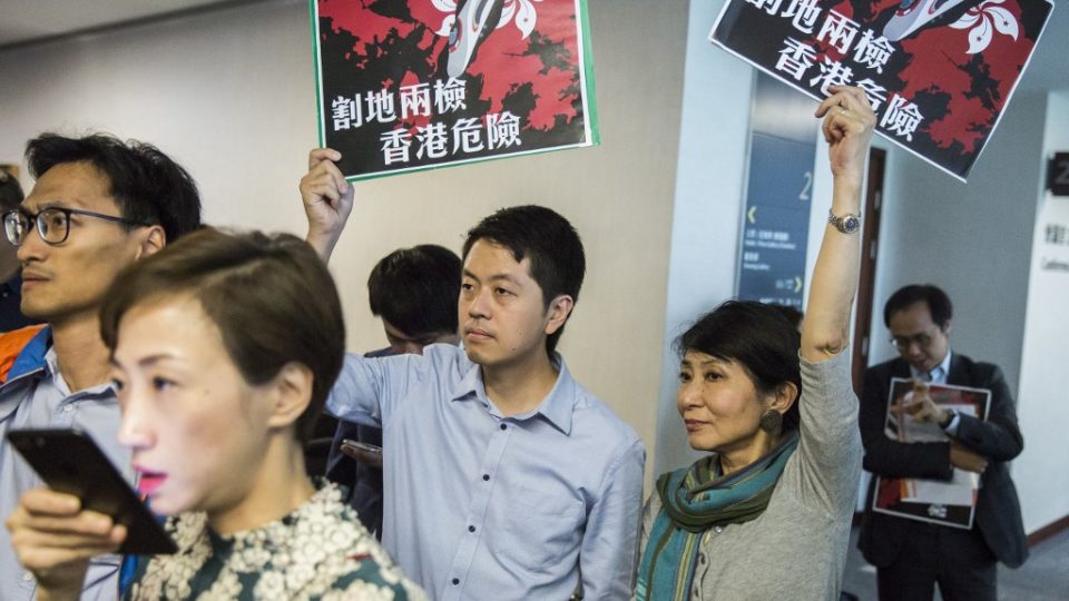 Pro-democracy lawmaker Ted Hui (center) holds a sign protesting a proposal to allow mainland police at West Kowloon Station at a press conference at the Legislative Council building last year. Photo via AFP.