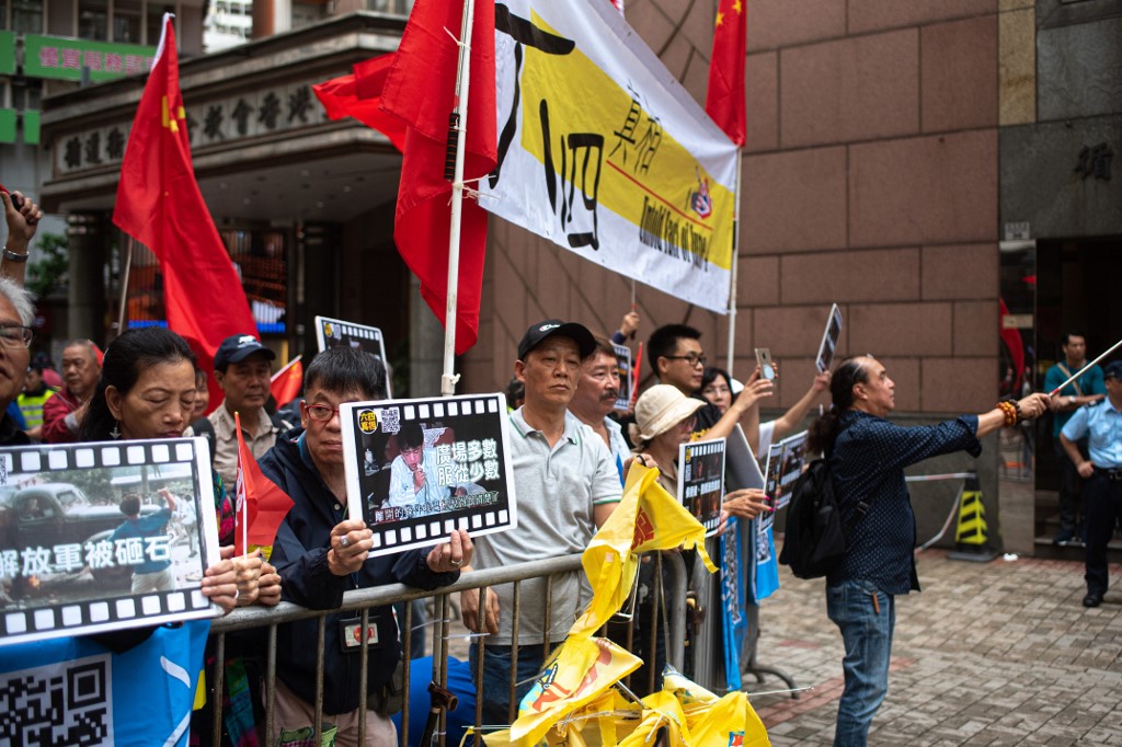 Pro-Beijing protesters hold placards as they chant slogans supporting Tiananmen crackdown during a march in Hong Kong yesterday. Photo via AFP.