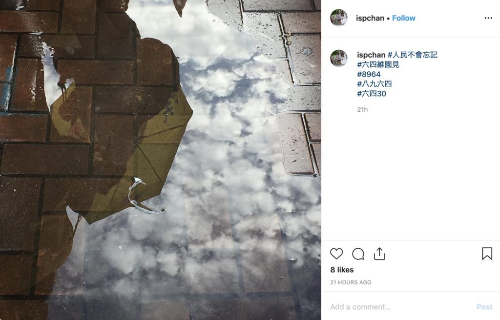 A marcher's yellow umbrella is reflected in a puddle during a demonstration commemorating the 1989 Tiananmen Square Massacre on Sunday. Photo via Instagram.