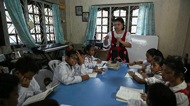 This picture taken on May 11, 2019 shows Sara Santa Maria, 50, teaching students the Kristang language at the Portuguese Settlement in Ujong Pasir, Malacca. Children in colourful outfits sing in a creole of Portuguese and Malay during a class in the historic Malaysian city of Malacca, part of efforts to stem the decline of the centuries-old language.