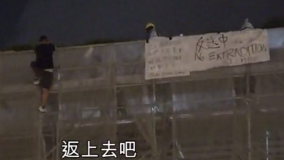 An anti-extradition bill protester clings to some scaffolding outside Pacific Place shortly before falling to his death. Screengrab via Apple Daily video.