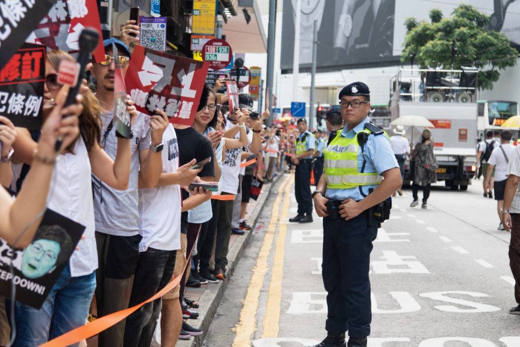 A policeman keeps order as tens of thousands of protesters wend their way through Hong Kong today. Photo by Samantha Mei Topp.