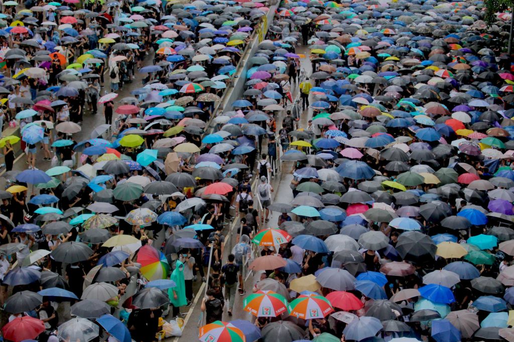 Protesters make way for people moving metal fences to the front line in order to build barriers protecting themselves from police during a protest against a controversial extradition bill. Photo by Vicky Wong.