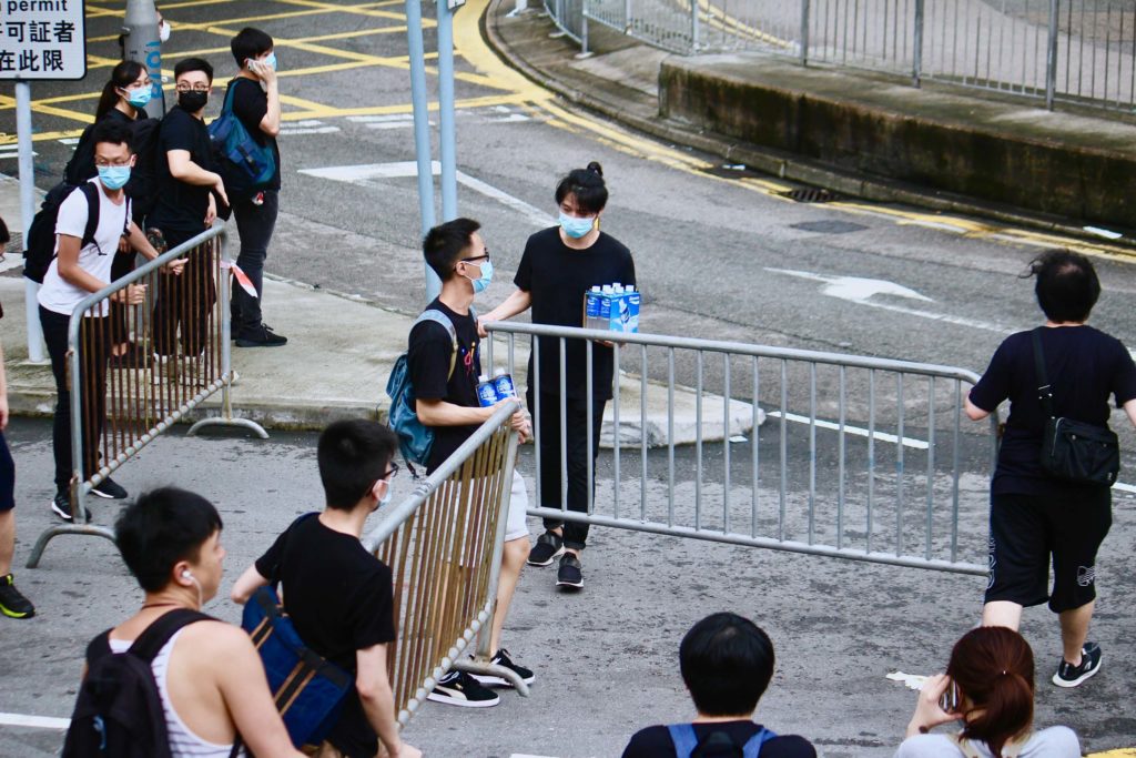 Protesters moving a metal fence in order to build barriers protecting themselves from police during a protest against a controversial extradition bill. Photo by Vicky Wong.