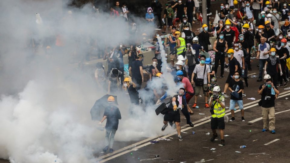 A protester throws a tear gas canister fired by police during a rally against a controversial extradition law proposal outside the government headquarters in Hong Kong on June 12. Photo via AFP.