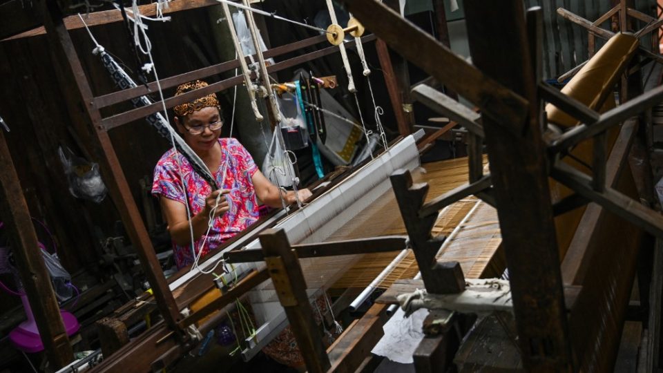 This photo taken on May 22, 2019 shows Rampai Sripetch, a 65-year-old Thai Muslim woman, weaving silk fabric on a loom at a workshop near Darul Falah mosque in Bangkok. Photo by Romeo Gacad / AFP