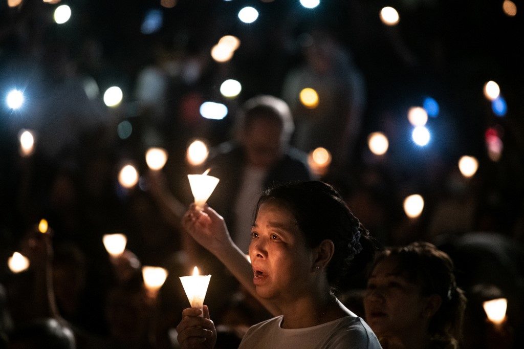 People hold candles at the vigil at Victoria Park last night. Photo via AFP.