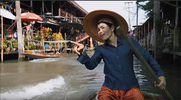 A floating market 'vendor' reacts to a blonde tower of Teutonic muscle blowing past her. Image: Red Bull / YouTube