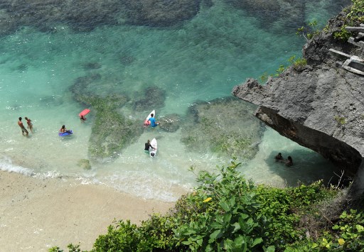 Tourists prepare to surf at Uluwatu beach. (Photo: Sonny Tumbelaka / AFP)