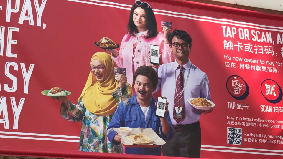An ad by E-Pay seen at Maxwell Food Centre showing Mediacorp artiste Dennis Chew portraying various races in Singapore. 