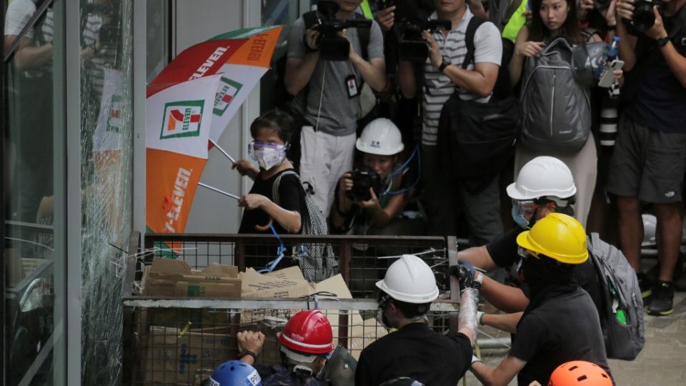 Protesters try to ram a metal cart through a closed entrance at the government headquarters yesterday. Photo via AFP.