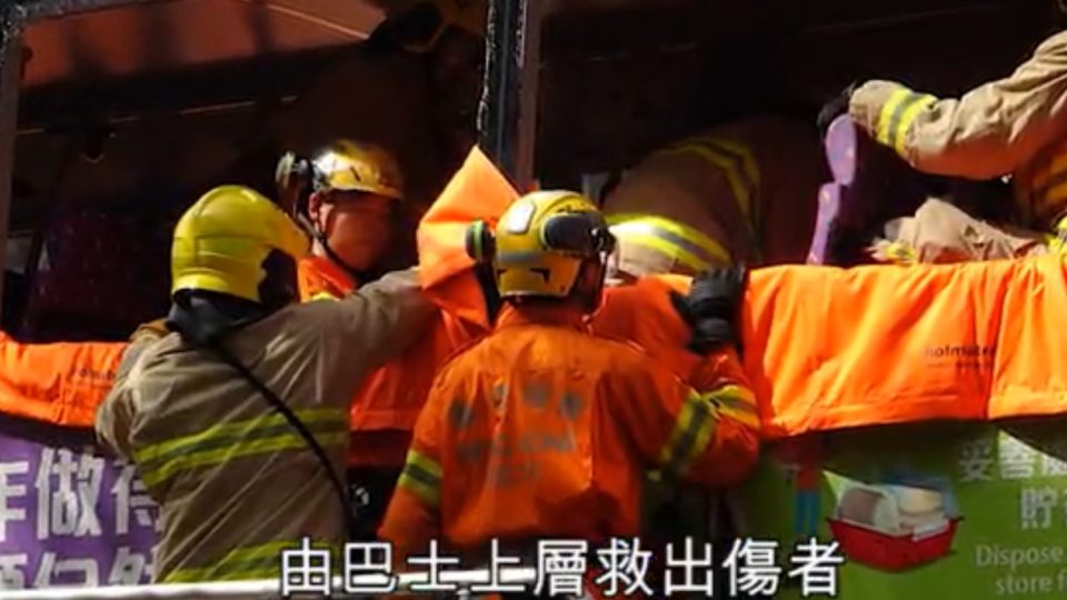Firefighters help people out of the upper level of a double-decker bus involved in a crash in the New Territories today. Screengrab via Apple Daily video.