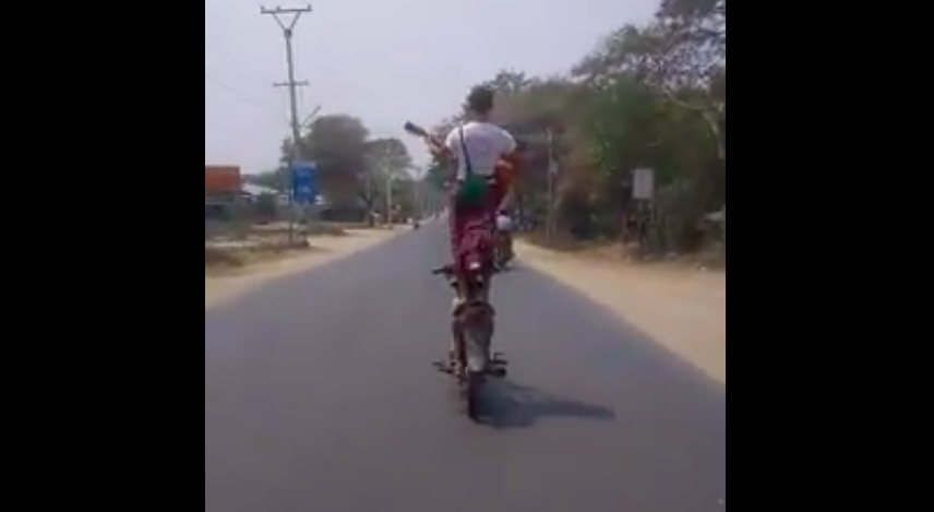 The man standing on the seat of a motorcycle while playing guitar, known as Myingyan King, in Myanmar. Screenshot via Facebook. 