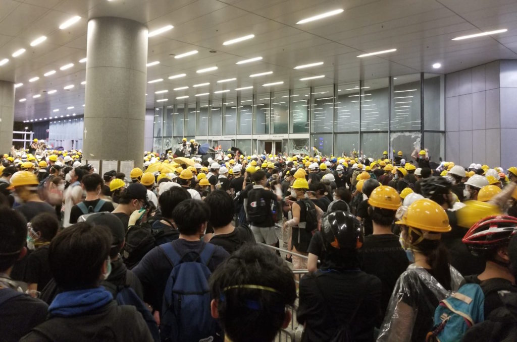 Protesters smash through the glass of the public entrance to the LegCo yesterday. Photo by Vicky Wong.