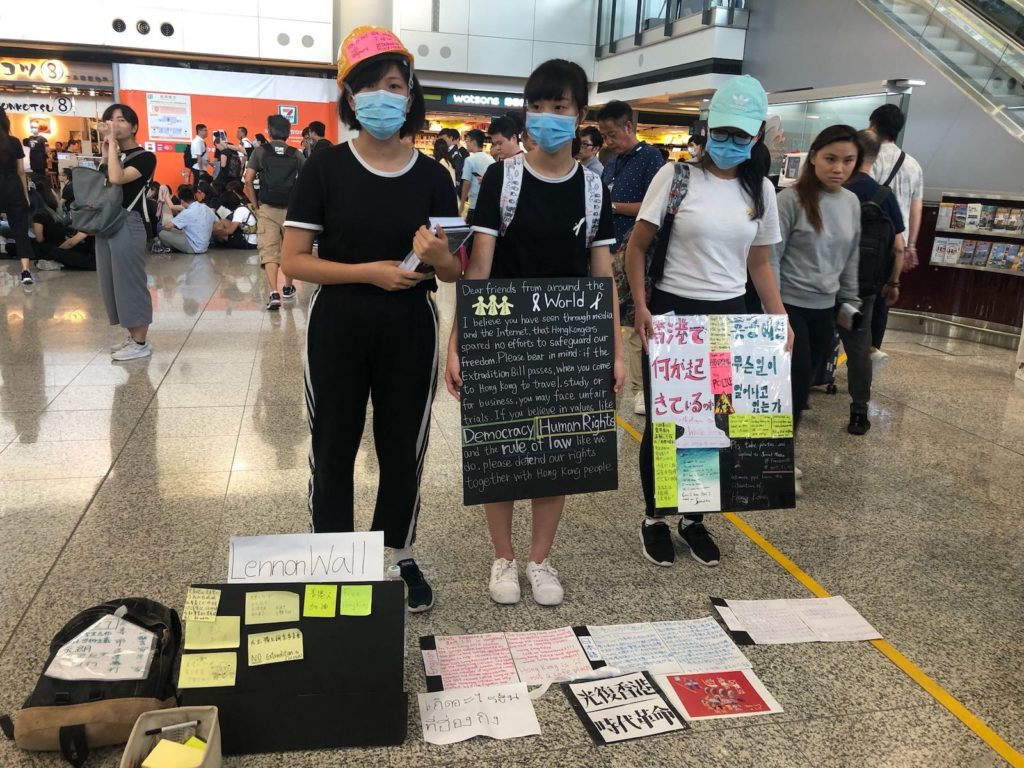 Protesters with signs in multiple languages with information about the protest movement. Photo by Iris To.