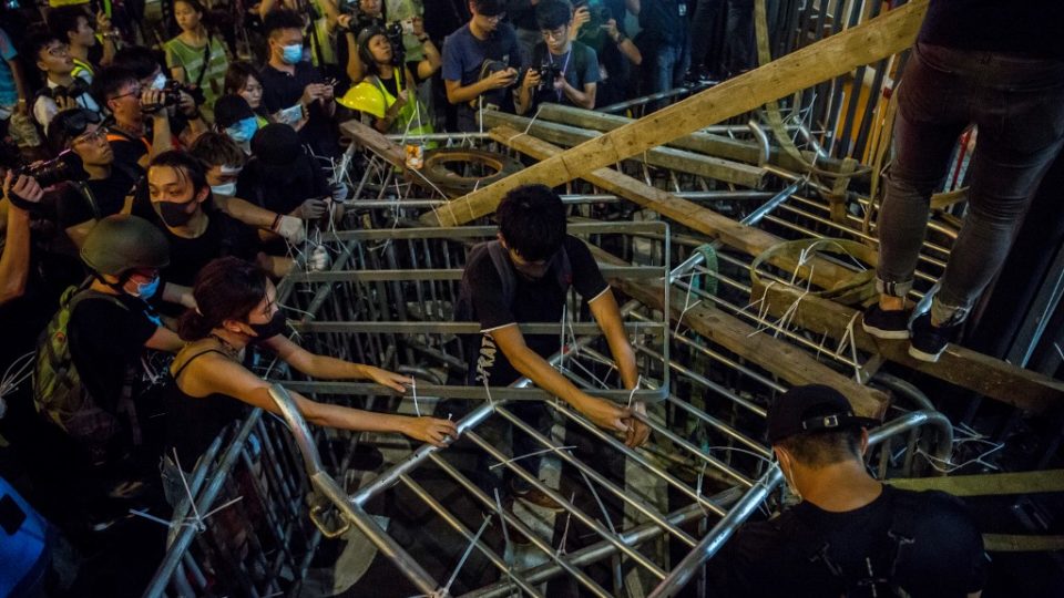 Protesters secure barricades to a gate of the police headquarters in Wan Chai during an unruly protest on June 26. Photo via AFP.