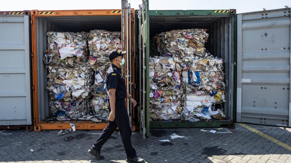 An Indonesian customs officer inspects containers filled with unauthorized trash originating from Australia. Photo via AFP.