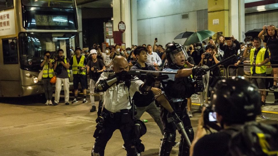 A police officer points a firearm during clashes with protesters who had gathered outside Kwai Chung police station. Photo via AFP.