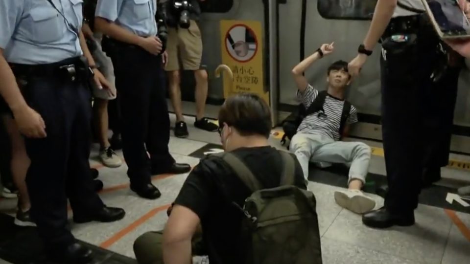 A young protester blocks an MTR train door at Admiralty MTR station. Screengrab via Facebook video/RTHK.