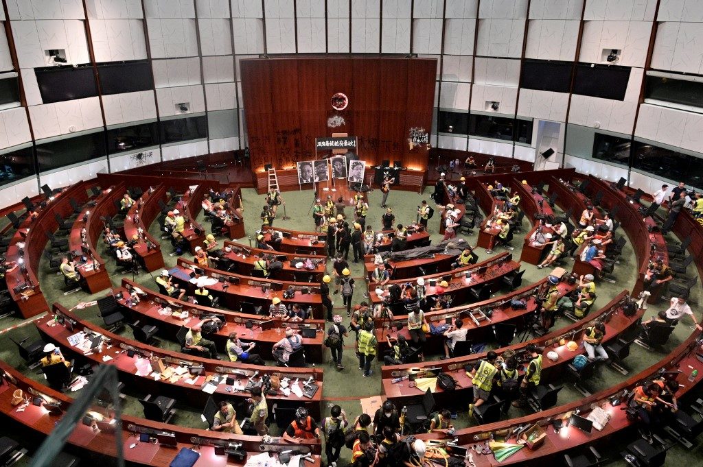 Protesters and members of the media are seen in the Hong Kong parliament chambers after protesters broke into the building today. Photo via AFP.