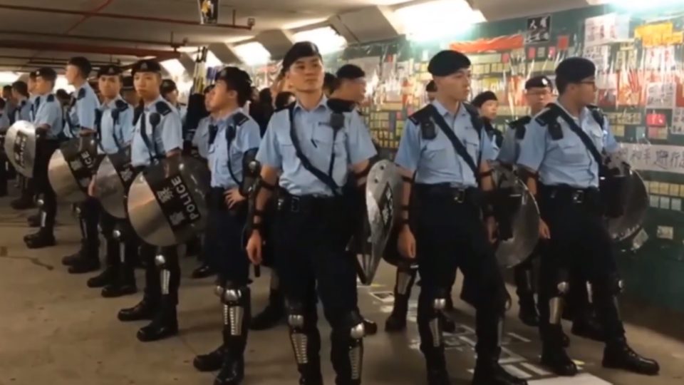 Cops in riot gear secure a pedestrian tunnel in Tai Po where the personal details of an officer were posted. Screengrab via YouTube.