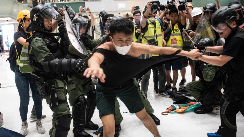 Police officers tear the shirt of a protester during a clash inside a shopping arcade in Sha Tin after a rally against a controversial extradition bill. Photo via AFP.