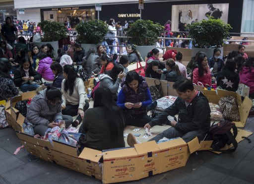 Filipino workers play cards as they relax on their day off in Hong Kong in February of 2018. Photo via AFP.