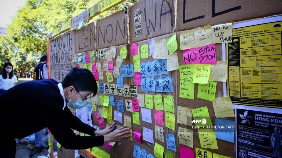 This photo taken on August 9, 2019 shows a supporter of the Hong Kong pro-democracy protests posting a note on a makeshift “Lennon Wall” at the University of Queensland in Brisbane. – Tensions in Hong Kong have rippled across Australian university campuses, prompting clashes between pro-democracy and pro-Beijing students, harassment and death threats. (Photo by Patrick HAMILTON / AFP)