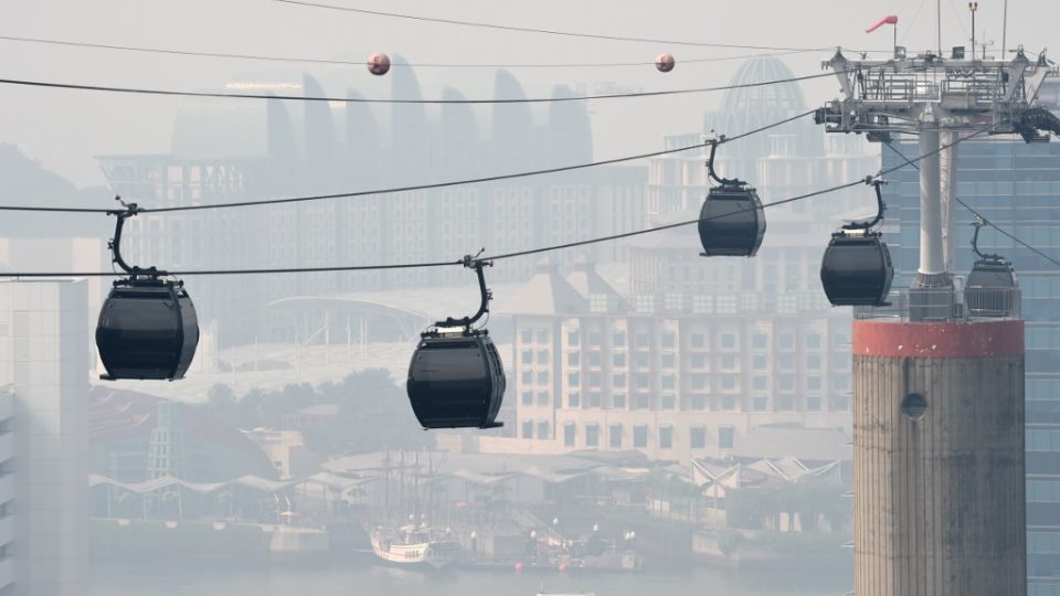 Cable cars ply across the Resort World Sentosa island while the skyline blanketed with haze in Singapore on August 26, 2016. – Smog and a strong acrid smell blanketed Singapore on August 26 as smoke from forest fires in Indonesia blew into the city-state, sending the air quality index to unhealthy levels. (Photo by ROSLAN RAHMAN / AFP)