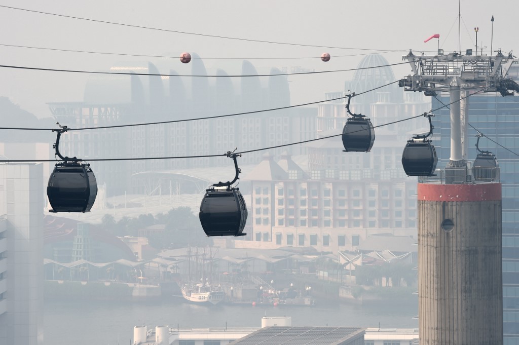 Cable cars ply across the Resort World Sentosa island while the skyline blanketed with haze in Singapore on August 26, 2016. – Smog and a strong acrid smell blanketed Singapore on August 26 as smoke from forest fires in Indonesia blew into the city-state, sending the air quality index to unhealthy levels. (Photo by ROSLAN RAHMAN / AFP)