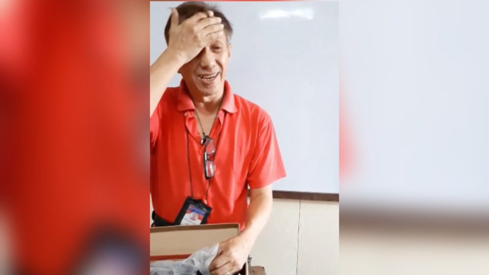 Science teacher Cesar Punzalan with the pair of shoes he received from his students. <i>Photo: Screenshot from Mary Anne Claire Garcia</i>
