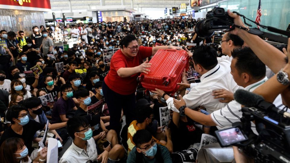 A tourist gives her luggage to security guards as she tries to enter the departures gate during another demonstration by pro-democracy protesters at Hong Kong International Airport on August 13, 2019. File photo via AFP.