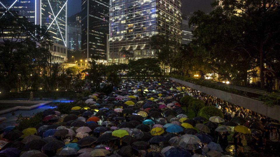 People from the finance community hold up umbrellas and shine lights during a protest in Central last night. Photo via AFP.