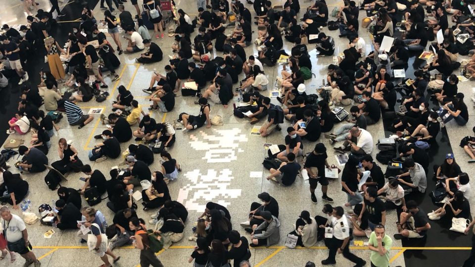 Protesters sit on the floor of Hong Kong International Airport today, surrounding a display with the characters for “Hong Kong” fashioned out of Post-It notes. Photo by Iris To.