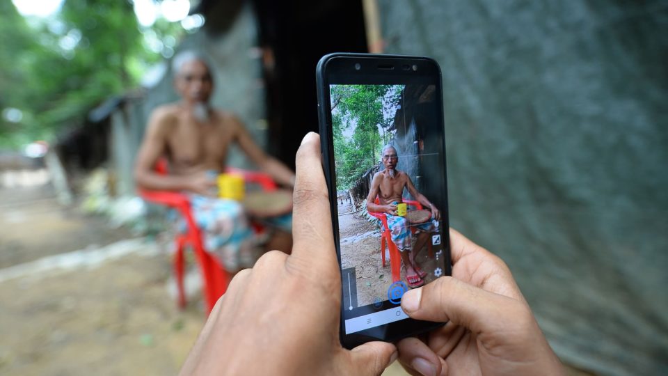 In this picture taken on July 23, 2019, Rohingya youth Mohammad Rafiq uses his mobile phone to take photos of a man by his shack at the Kutupalong refugee camp.  Photo by Munir Uz Zaman/AFP