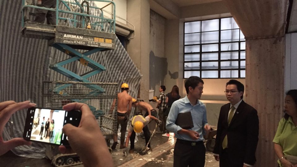 Lawmaker Ted Hui (blue shirt) and District Councillor Ng Siu-hong (black jacket) speak at a pedestrian passageway where a sizeable portion of the ceiling collapsed today. Photo by Stuart White.